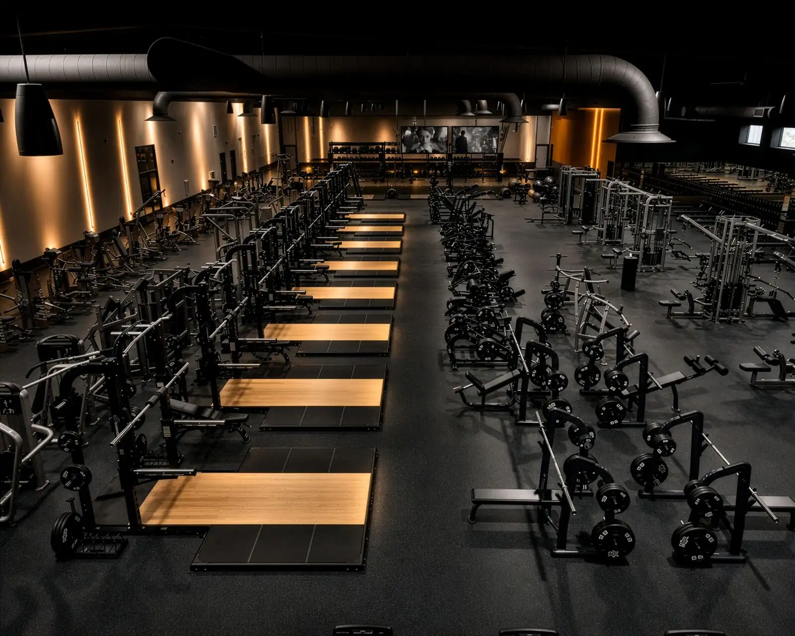 Wide view of the strength floor with wood lifting platforms and plate-loaded machines at Sanctuary Fitness Marlboro