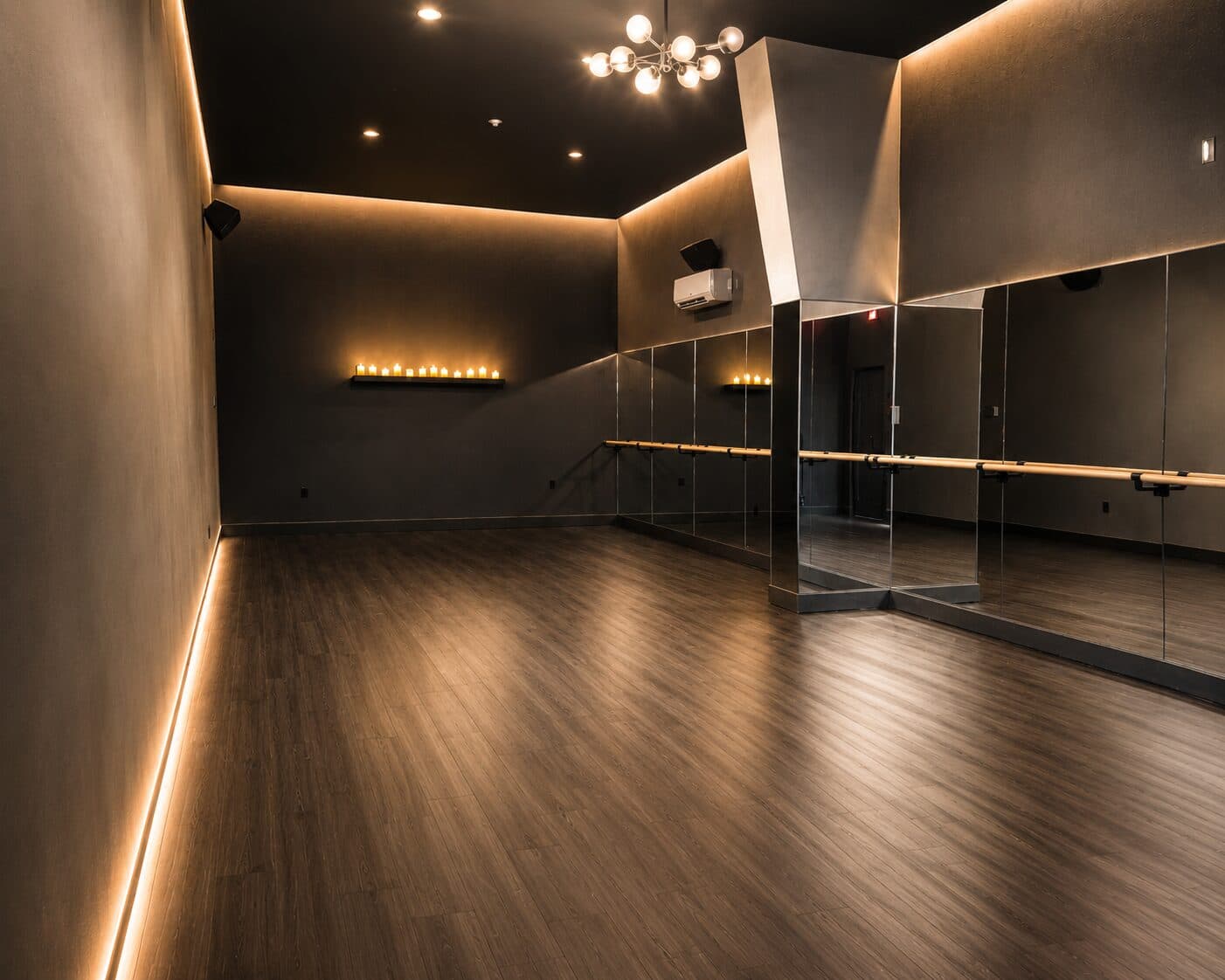Alternate view of the Sanctuary Fitness movement studio, with warm accent lighting and full-height mirrors.